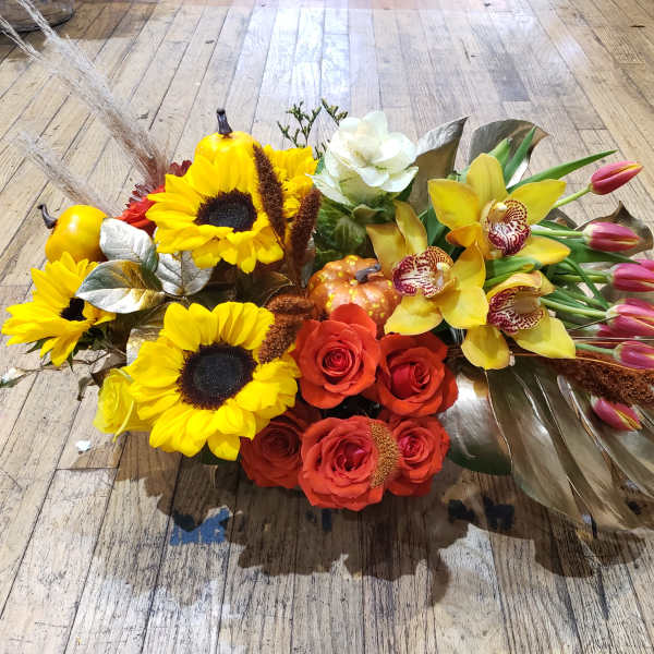 Mixed bouquet with sunflowers, roses, orchids, and tulips on a wooden floor