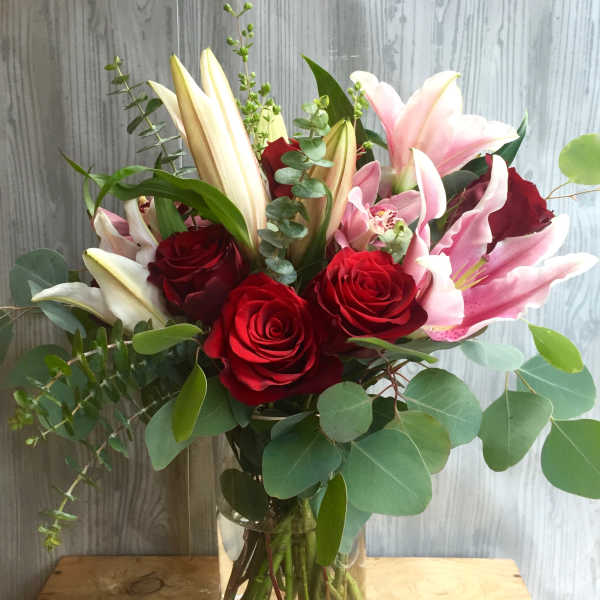 Bouquet of red roses and pink lilies in a clear glass vase