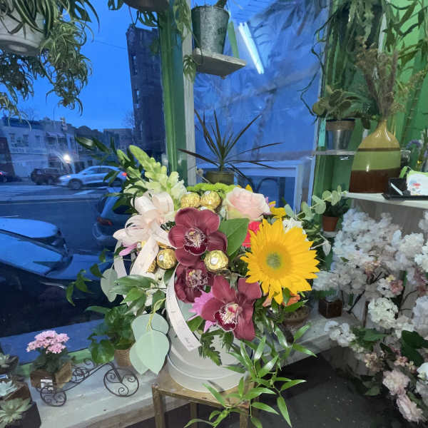 Mixed flower arrangement in a white bucket with a yellow gerbera daisy and orchids