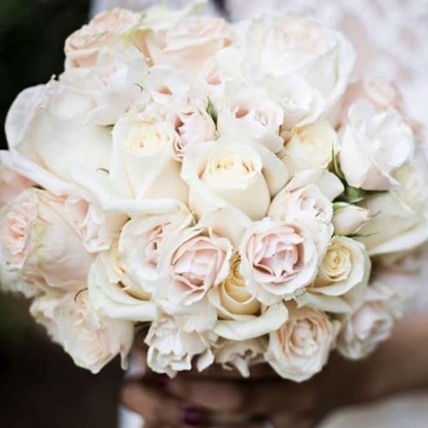 Bride holding a bouquet of white and blush roses