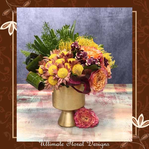 Mixed bouquet in a gold pedestal vase with pink and yellow flowers