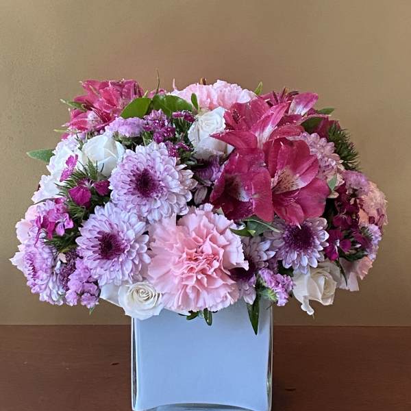 Pink and white floral arrangement in a square glass vase