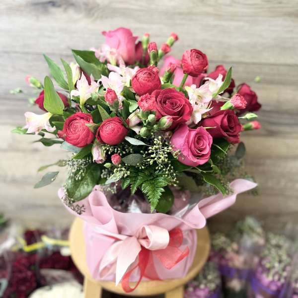 Pink and red rose bouquet in a pink wrapped container with ribbon