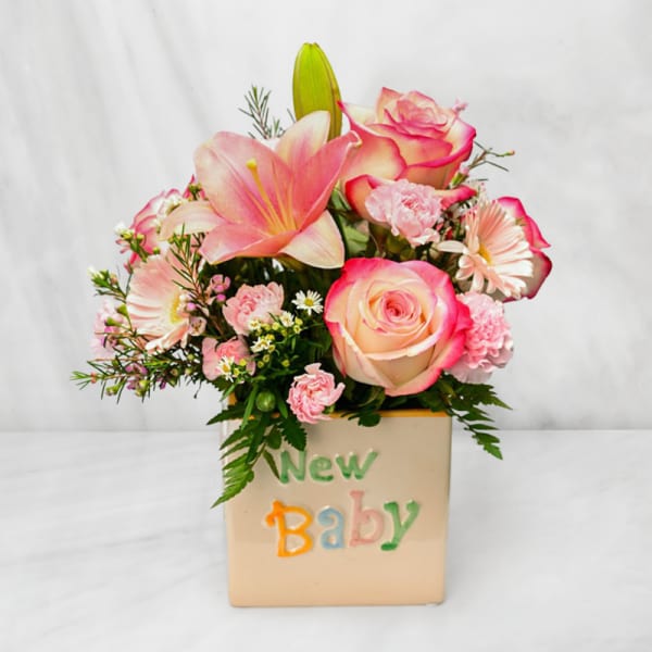 Pink and cream floral arrangement in a "New Baby" container