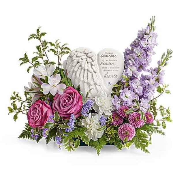 Floral sympathy arrangement with pink roses and lavender flowers around a heart plaque