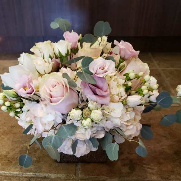 Soft pink and white bouquet with roses and eucalyptus in a low container