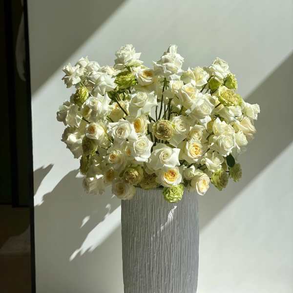 White roses arranged in a tall textured vase