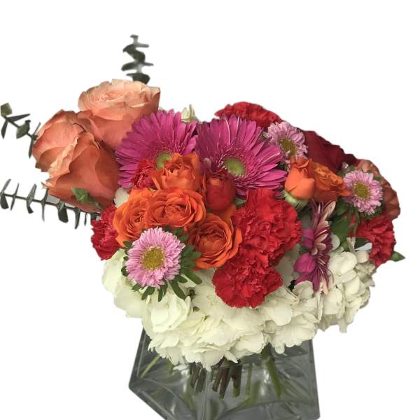 Mixed bouquet of orange, pink, red, and white flowers in a glass vase