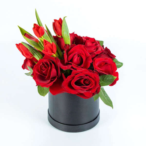 Red roses and tulips arranged in a black round box