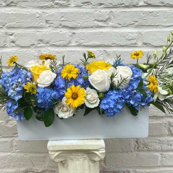Blue and white floral arrangement in a rectangular white container
