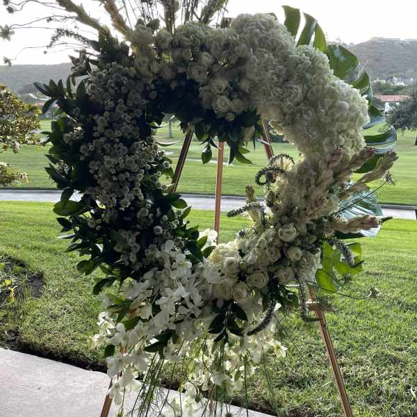 Large white floral wreath on a stand with cascading orchids