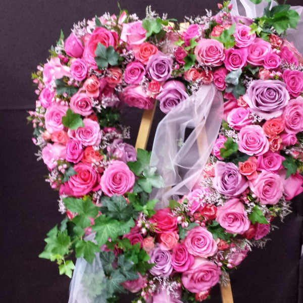 Heart-shaped floral wreath of pink and purple roses on an easel