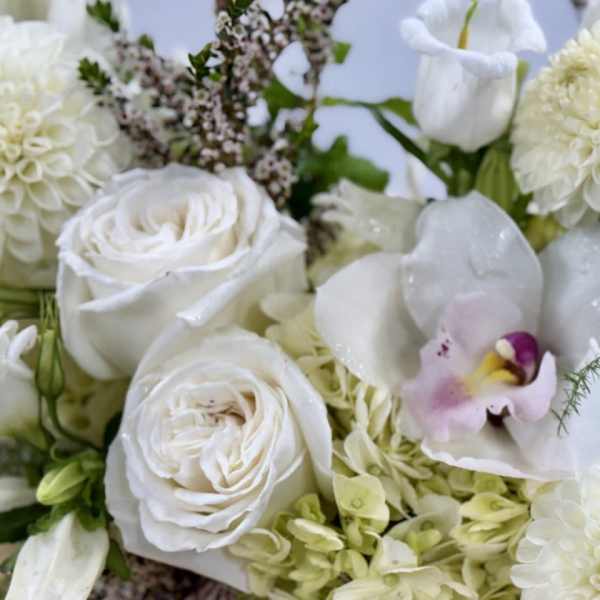 White roses and dahlias with a pale orchid in a floral arrangement