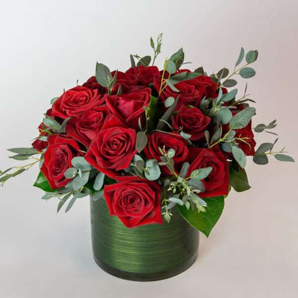 Red roses arranged in a green cylindrical vase