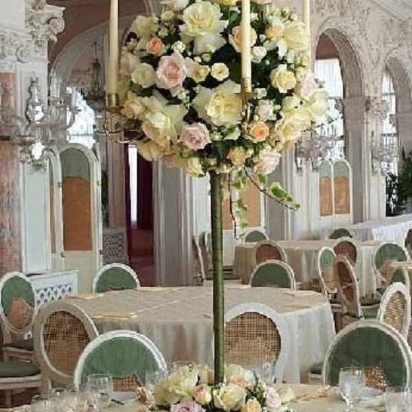 Tall floral centerpiece with pale roses and candles on a banquet table