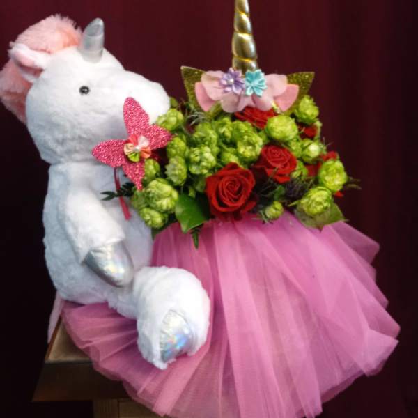 Plush unicorn holding a bouquet of red roses and green blooms