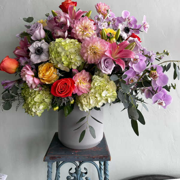Mixed bouquet in a white vase with pink, purple, and red blooms