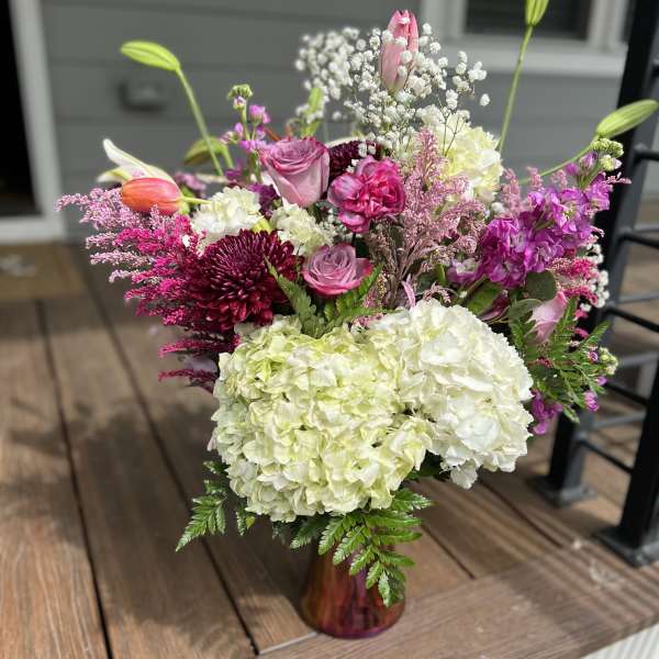 Mixed bouquet in a burgundy vase with pink, white, and purple flowers