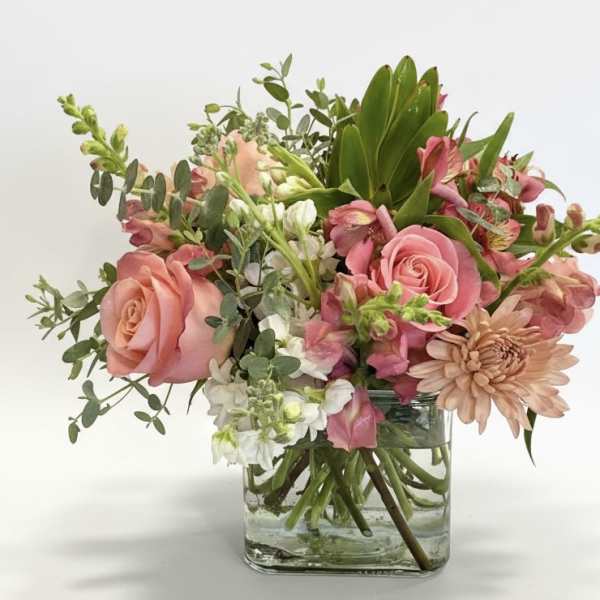 Pink roses and mixed flowers arranged in a clear glass vase