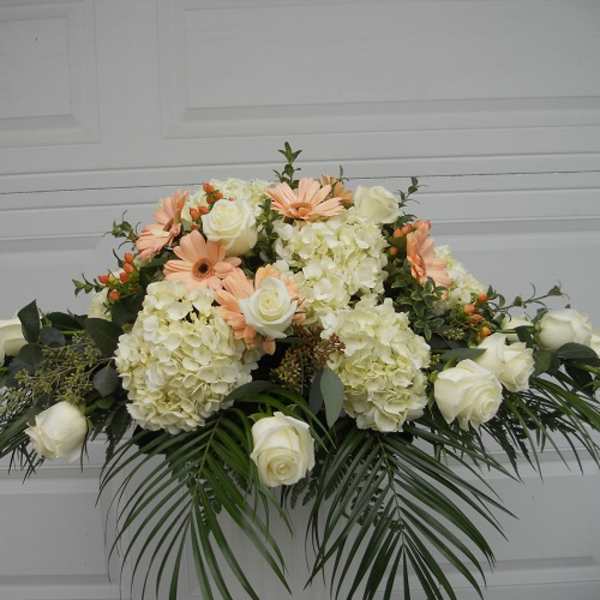 White roses and pale peach daisies in a low floral arrangement