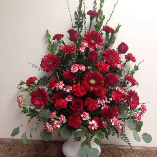 Red roses and gerbera daisies in a white vase