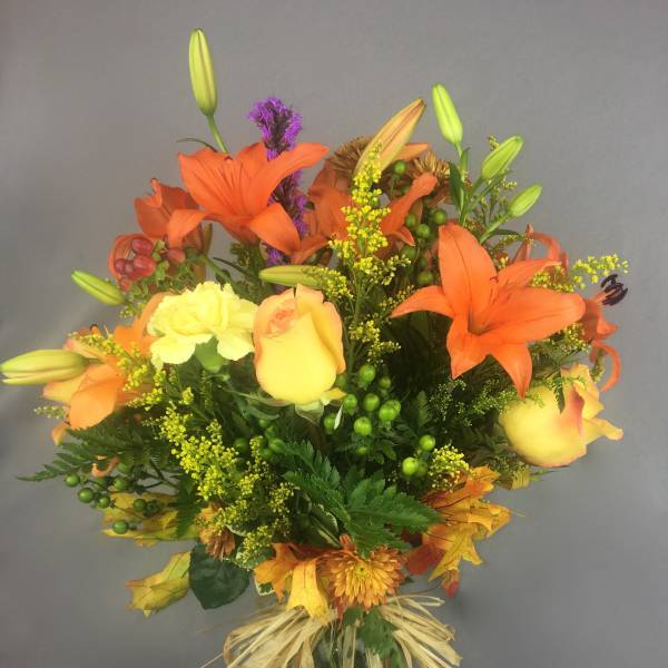 Bouquet of orange lilies and yellow roses in a glass vase
