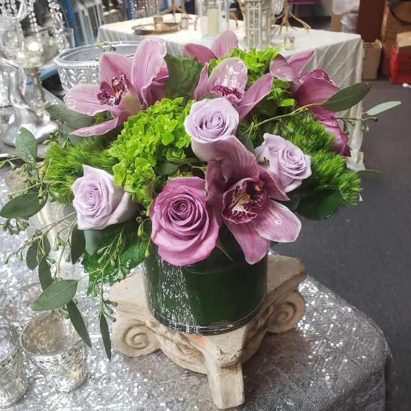 Lavender roses and pink orchids in a dark vase