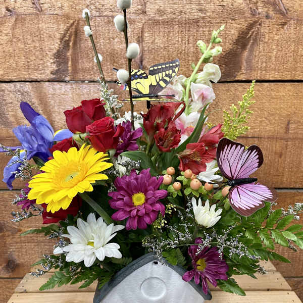 Colorful flower arrangement in a butterfly-decorated house-shaped container