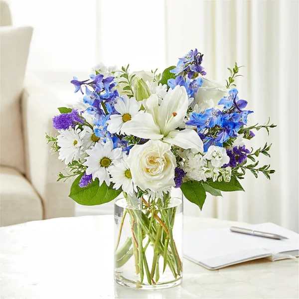 White and blue mixed bouquet in a clear glass vase