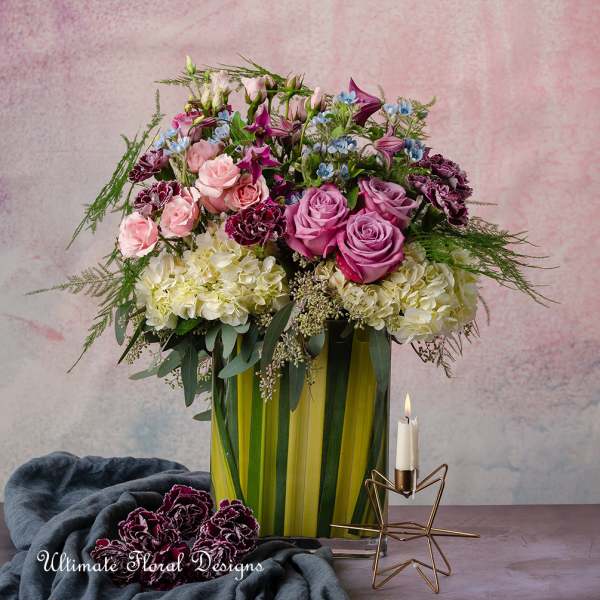 Mixed bouquet of pink and purple roses in a tall striped vase