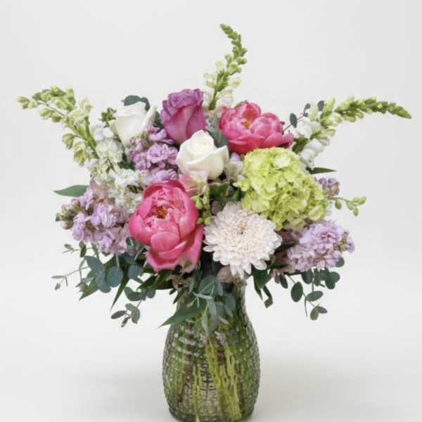 Pink and white flower arrangement in a textured glass vase