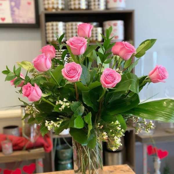 Pink roses arranged in a clear glass vase with greenery