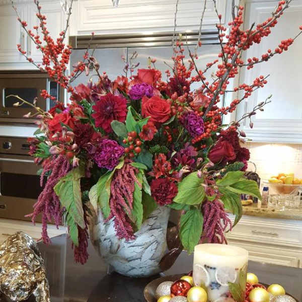Large red and purple floral arrangement in a decorative vase on a table