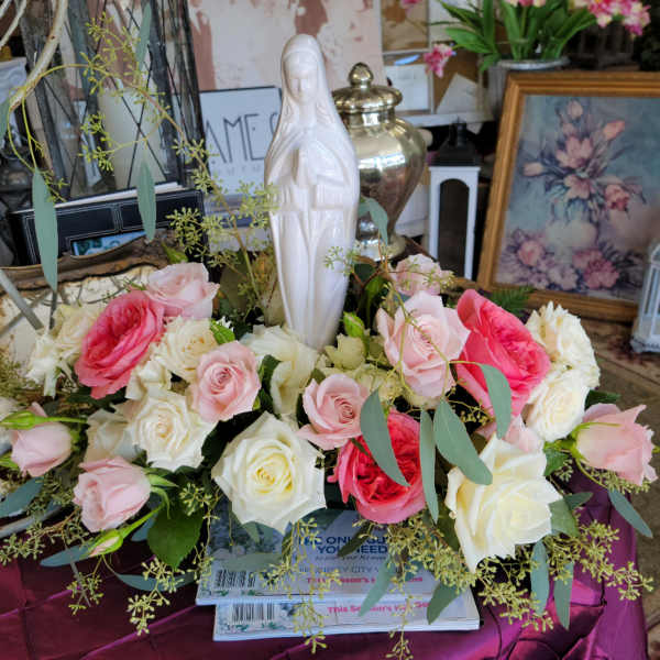 Pink and white roses arranged around a white statue