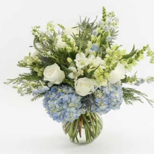 White roses and blue hydrangeas in a glass vase