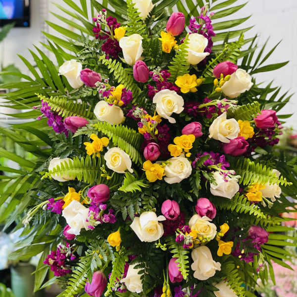 Large floral spray with white roses, pink tulips, and yellow accents