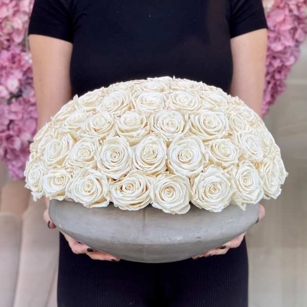 Large dome of white roses in a gray bowl vase