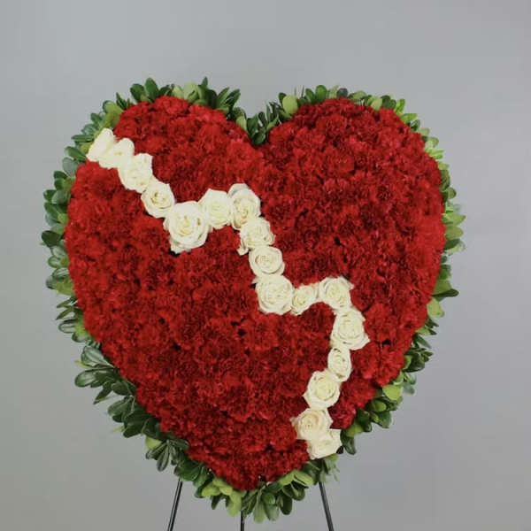 Heart-shaped red floral wreath with white roses on a stand