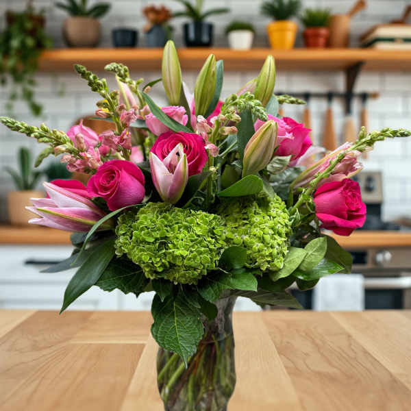 Pink roses and lilies arranged in a clear glass vase