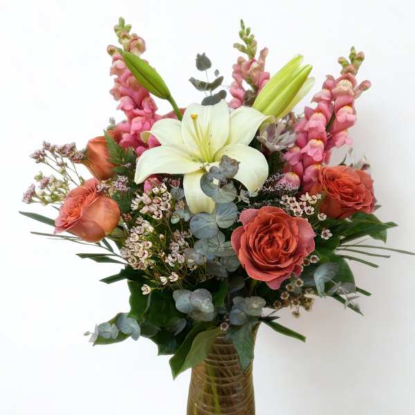 Bouquet of lilies, roses, and pink snapdragons in a glass vase
