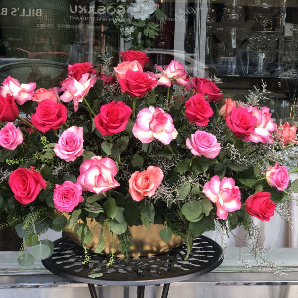 Large arrangement of pink and red roses in a gold bowl