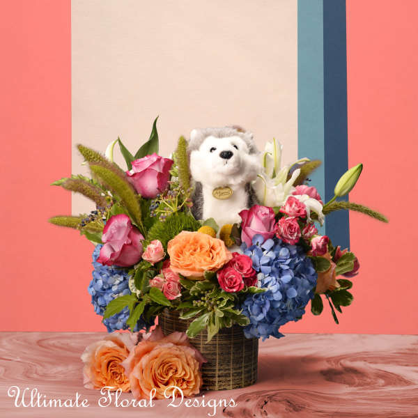 Floral arrangement with roses, hydrangeas, and a plush husky in a vase