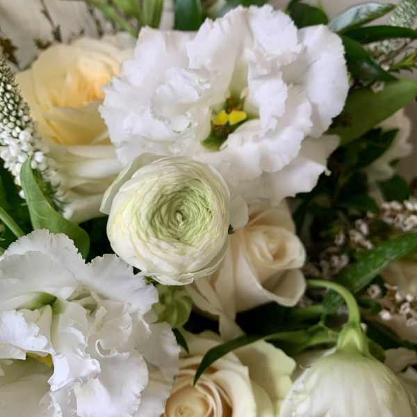 Close-up bouquet of white and cream flowers with green accents