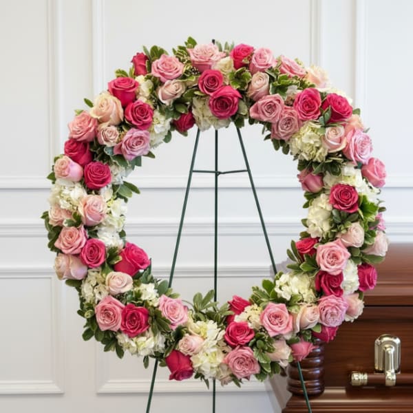 Heart-shaped wreath of pink and white roses on a stand