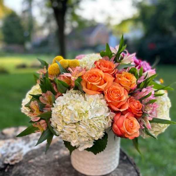 Bouquet of orange roses and white hydrangeas in a white vase