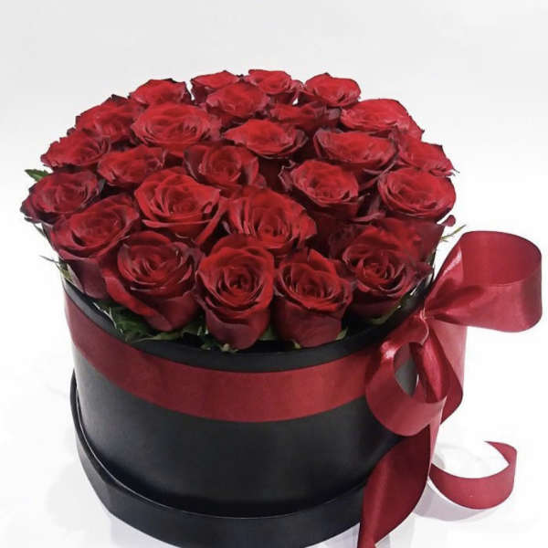 Red roses arranged in a black round box with a red ribbon