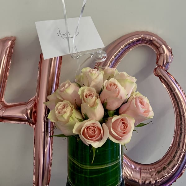 Pink roses in a green vase with rose-gold 40 balloons behind them