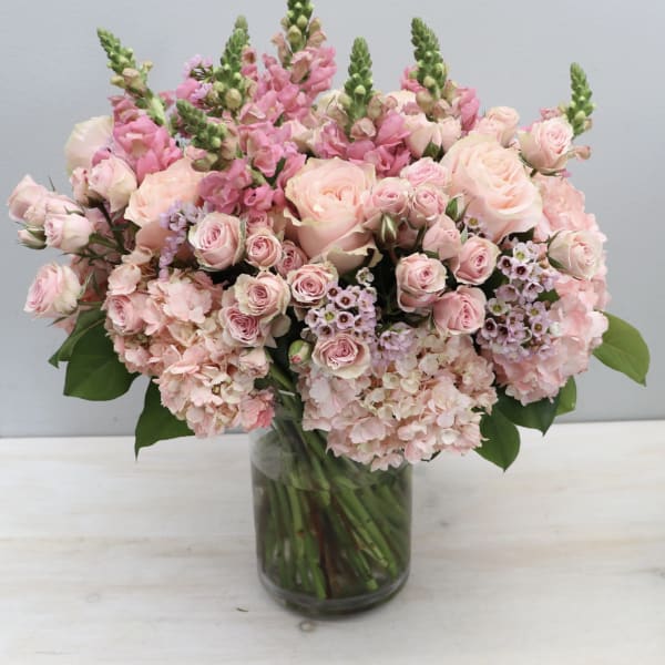 Pink roses and snapdragons arranged in a glass vase