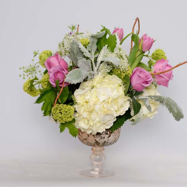 Pink roses and white hydrangea in a glass pedestal vase