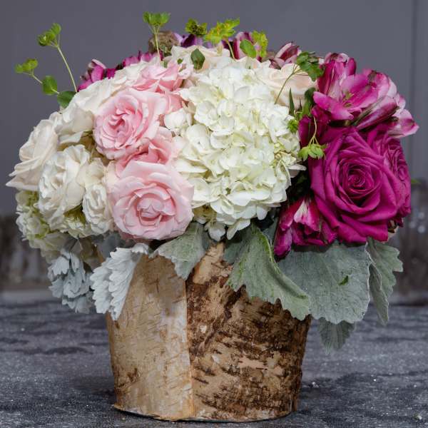 Pink and white floral arrangement in a birch bark container